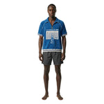 Model wearing blue terry cloth cabana shirt with half zip collar and mesh chest pocket with Statue of Liberty soccer patch.
