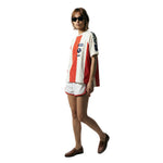 Female model wearing a white and red striped terry cloth short sleeve shirt with FIFA World Cup 26 patches on the chest and sleeve, paired with white athletic shorts.