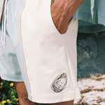 close up of shorts with embroidered oyster motif as man places hand in the pocket