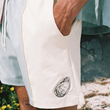 close up of shorts with embroidered oyster motif as man places hand in the pocket