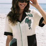 Female model wearing Tombarolo cabana shirt with sunglasses on, smiling