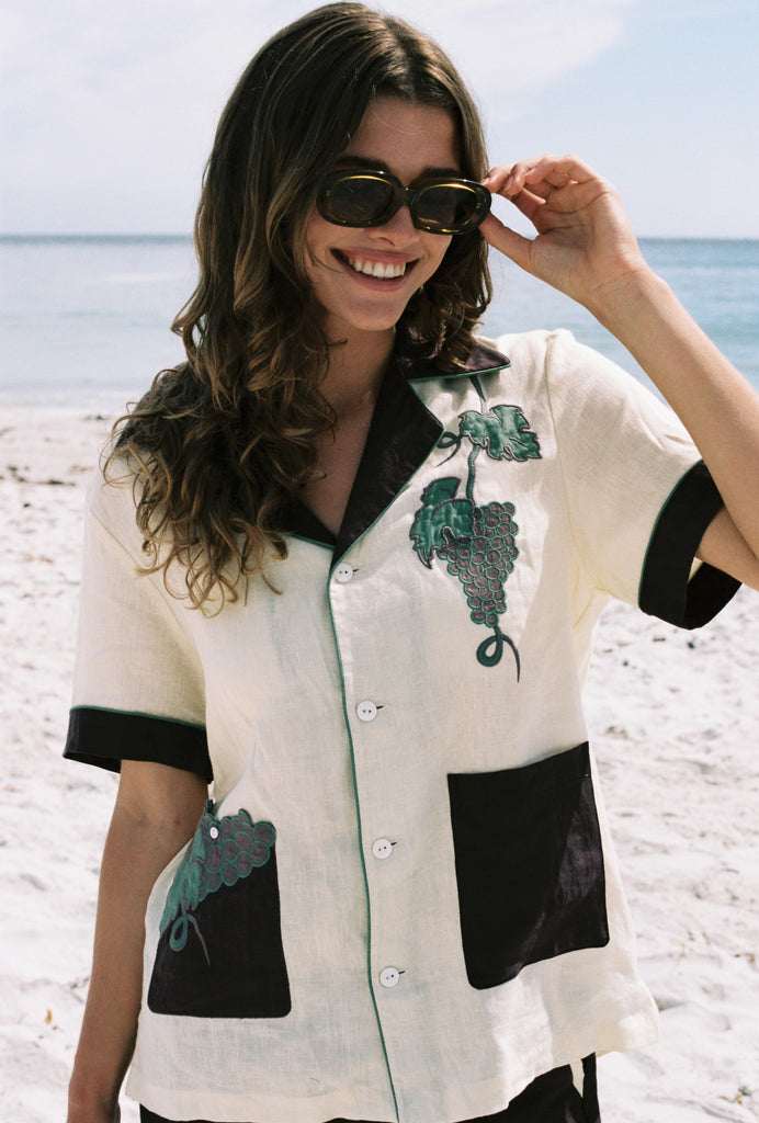 Female model wearing Tombarolo cabana shirt with sunglasses on, smiling