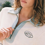 close up of woman wearing terry cloth embroidered oyster shirt holding zipper