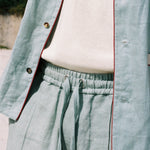 close up of on-model blue Linen tombolo pants with elastic waistband and drawstring, bottom of Tombolo Billion Oyster Project linen shirt also pictured