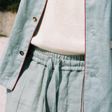 close up of on-model blue Linen tombolo pants with elastic waistband and drawstring, bottom of Tombolo Billion Oyster Project linen shirt also pictured
