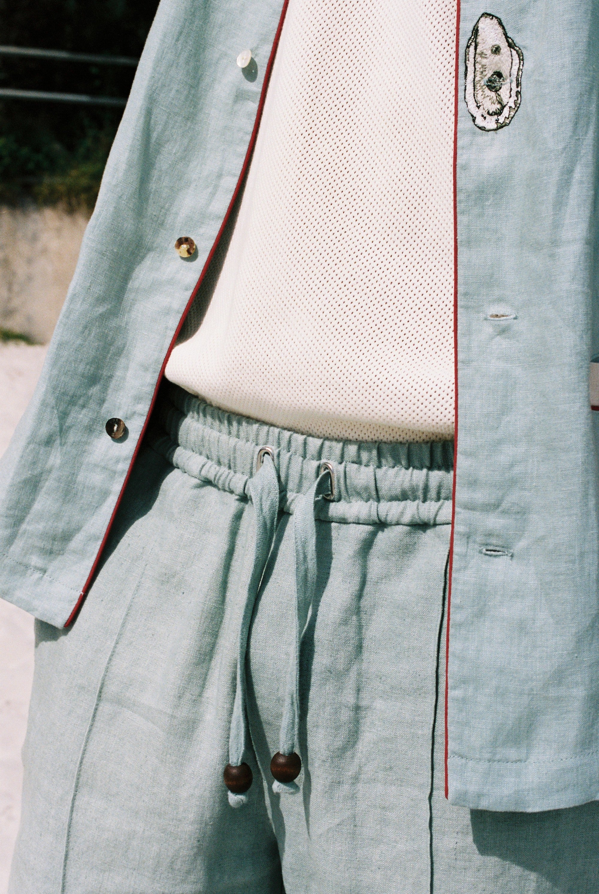close up of on-model blue Linen tombolo pants with elastic waistband and drawstring, bottom of Tombolo Billion Oyster Project linen shirt also pictured