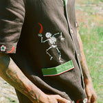 Close up view of embroidered skeleton holding a chili pepper. 