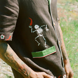 Close up view of embroidered skeleton holding a chili pepper. 