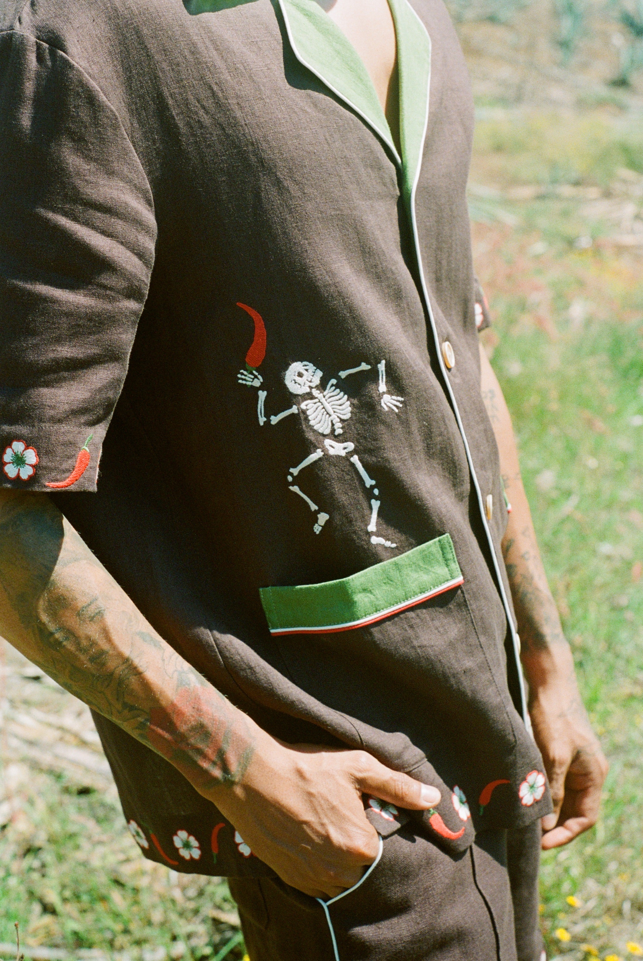 Close up view of embroidered skeleton holding a chili pepper. 