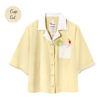 Light yellow short-sleeve button-up shirt with a white collar and pocket. The pocket has embroidered lime and chili pepper details. White beaded trim on the sleeves. Small sticker that reads "Crop Cut"
