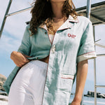 woman closes her eyes wearing the linen shirt with one button done up