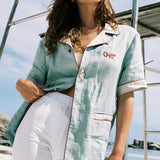 woman closes her eyes wearing the linen shirt with one button done up