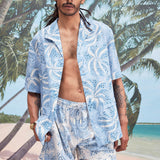 Male model with dreadlocks wearing an unbuttoned 'Palm Fronds (blue)' alongside matching 'Palm Fronds (blue) Swim Trunks,' all shot on a background with palm trees, sun, and a beach. 
