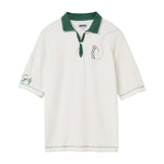 White terry cloth polo shirt with a forest green collar, placket, and stitching. Features an embroidered golfer on the left chest swinging a club, with a dotted line tracing the ball’s path. The left sleeve has green script embroidery reading 'Golf'.
