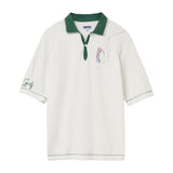 White terry cloth polo shirt with a forest green collar, placket, and stitching. Features an embroidered golfer on the left chest swinging a club, with a dotted line tracing the ball’s path. The left sleeve has green script embroidery reading 'Golf'.