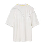 Back of a white terry cloth polo shirt with a yellow-trimmed collar. A curved black dotted line is embroidered across the upper back and shoulders, mimicking the motion of a tennis ball in play.