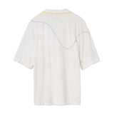 Back of a white terry cloth polo shirt with a yellow-trimmed collar. A curved black dotted line is embroidered across the upper back and shoulders, mimicking the motion of a tennis ball in play.