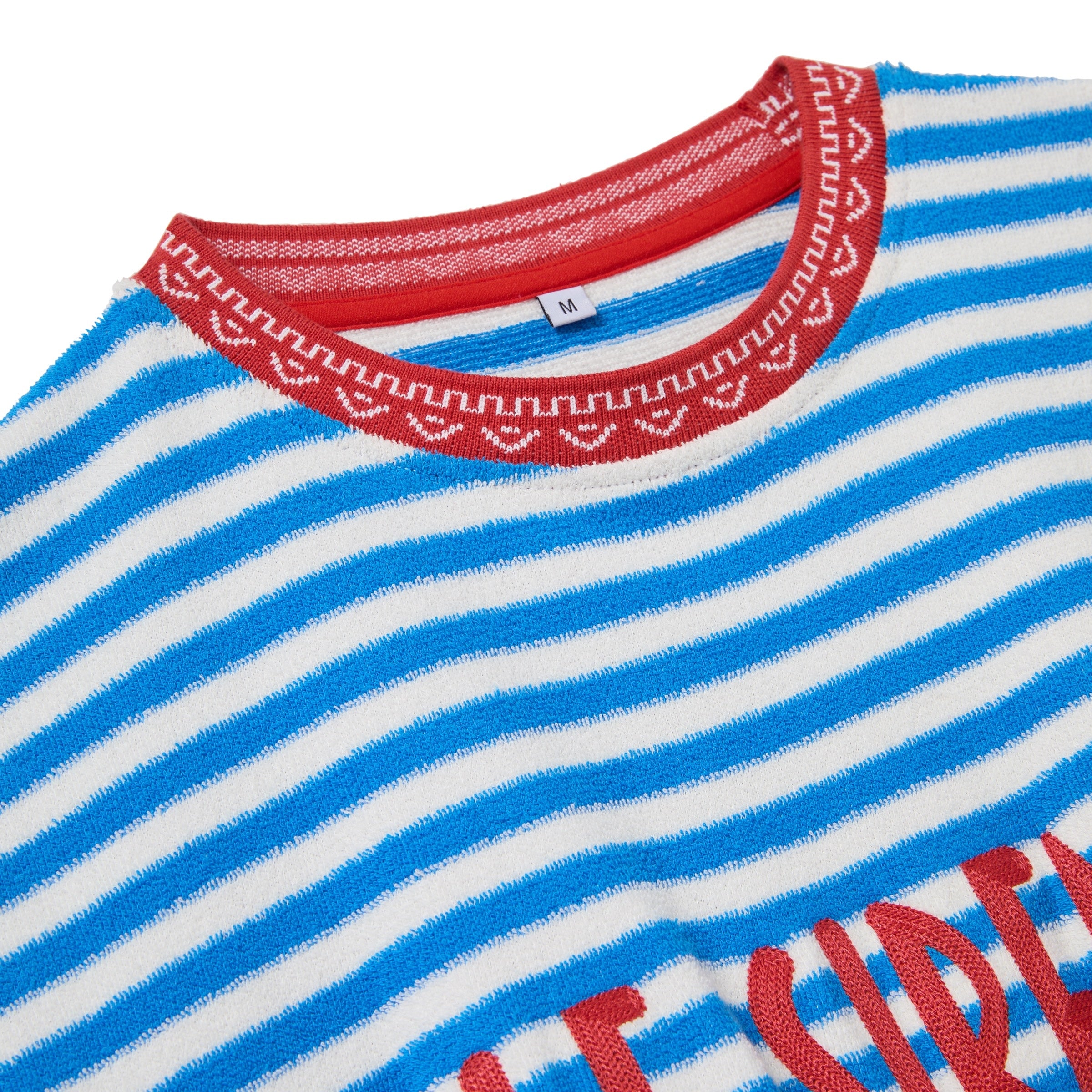 Close-up of a blue and white striped garment with red trim and text.