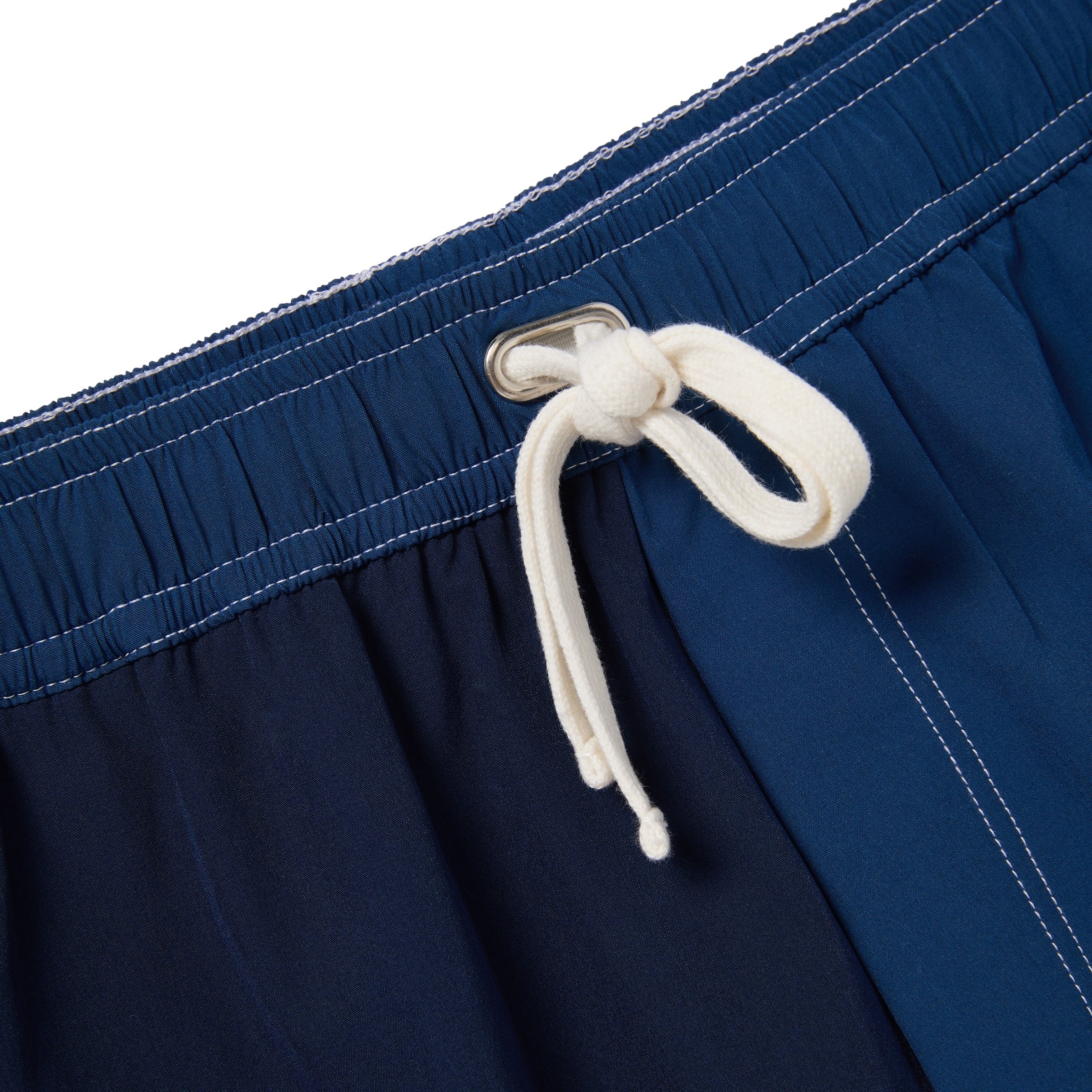 Close-up of navy blue trunks with a white drawstring on a white background