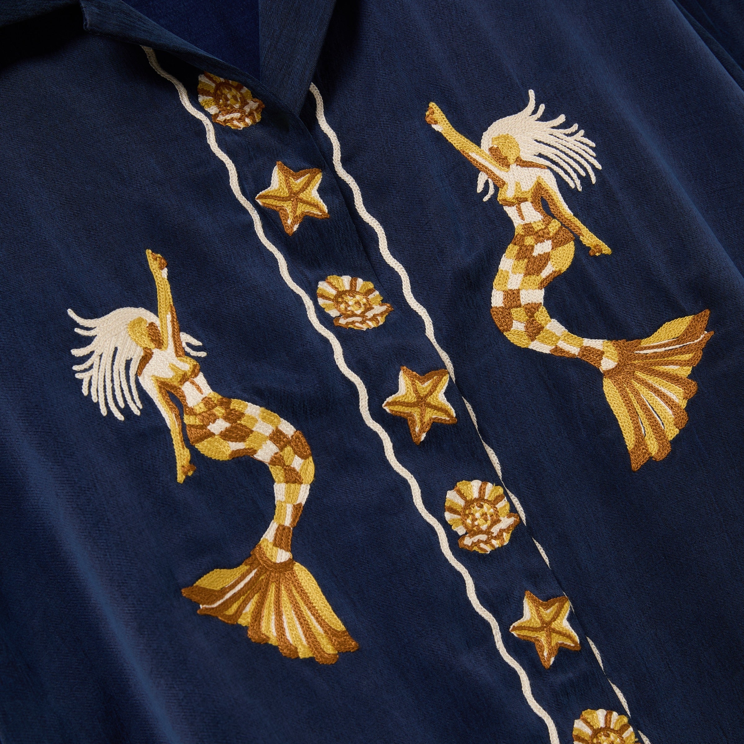 Embroidered mermaid and starfish design on a navy blue fabric