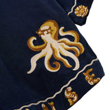 Embroidered octopus design on a dark blue fabric with gold and white accents.
