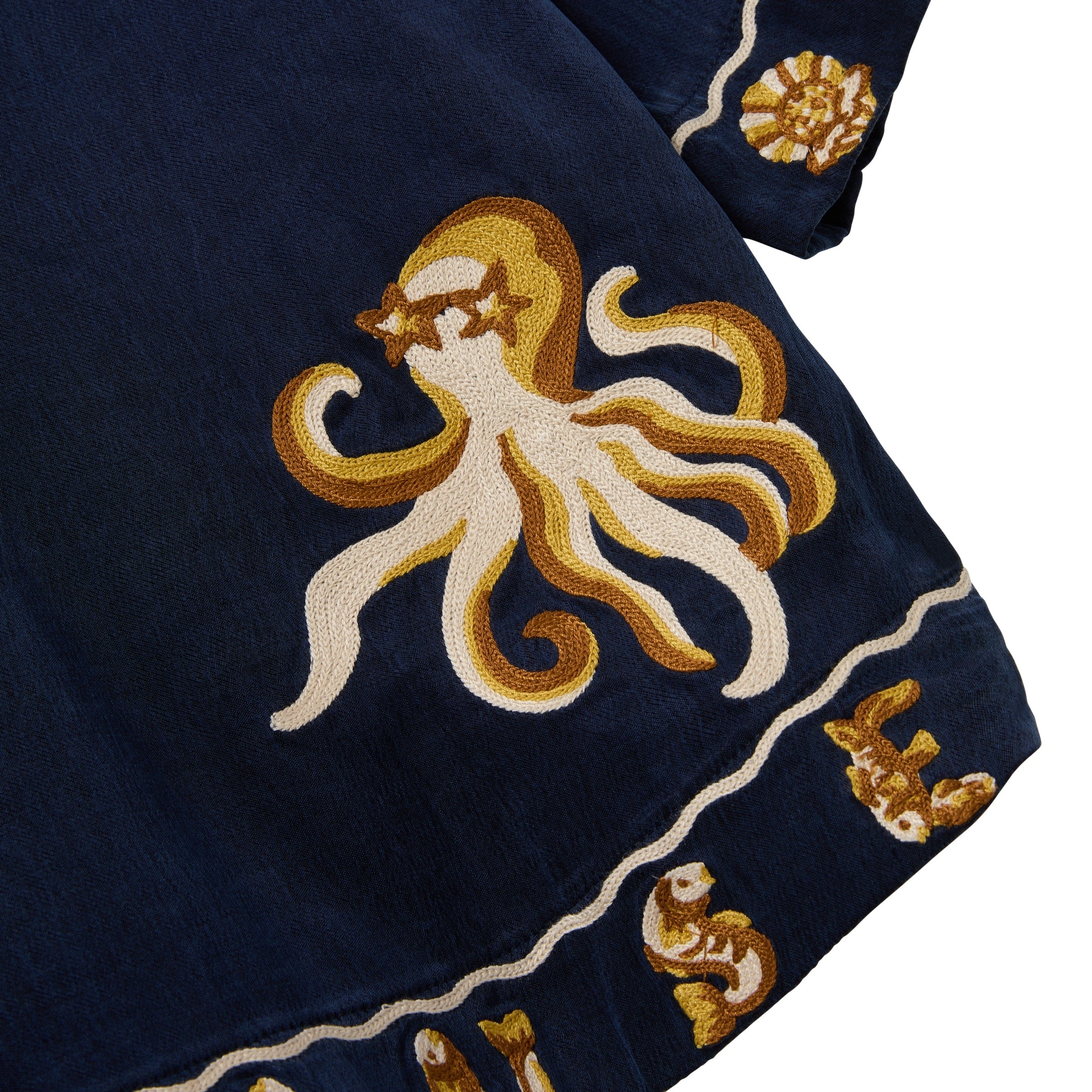 Embroidered octopus design on a dark blue fabric with gold and white accents.