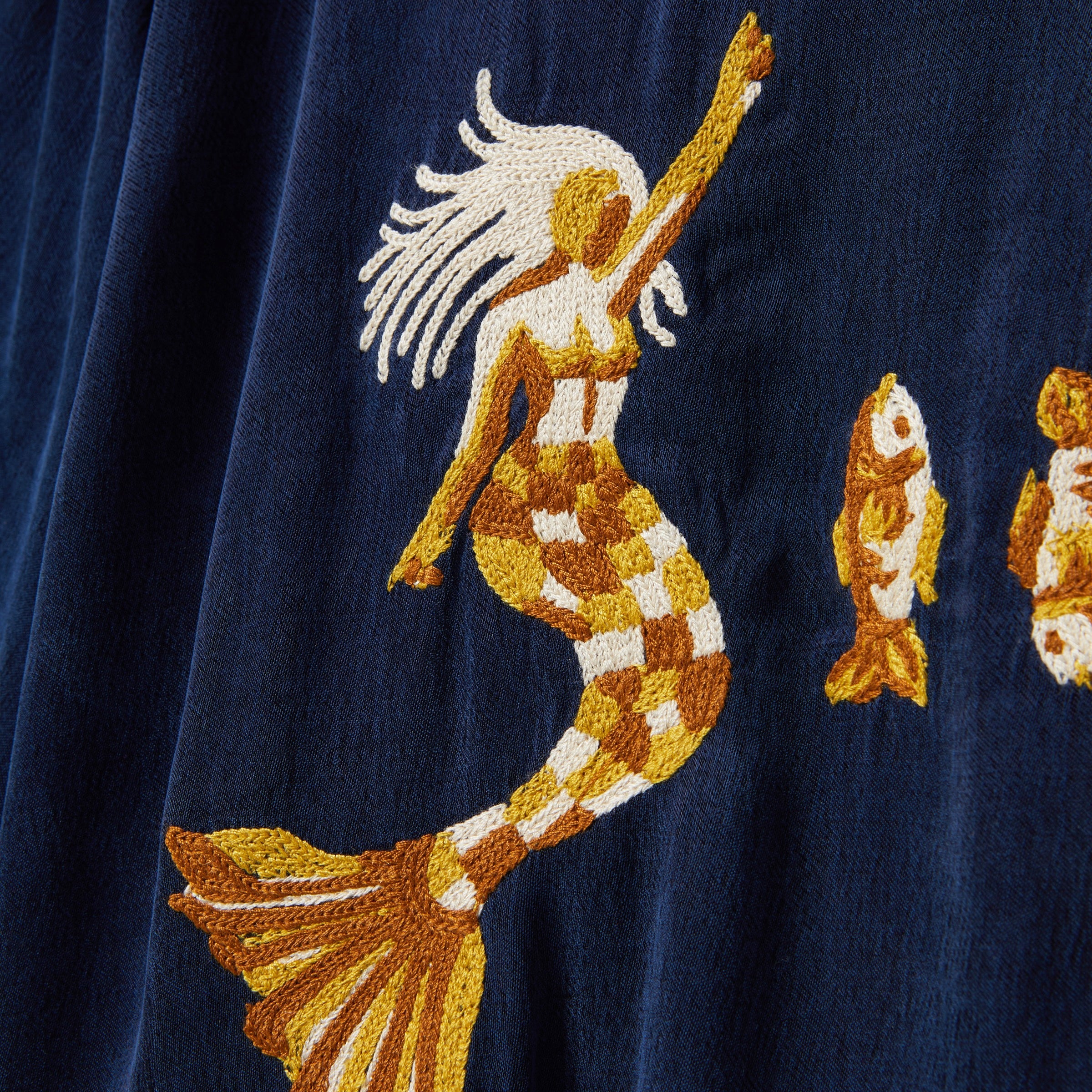 Embroidered mermaid and fish design on a navy blue fabric background