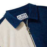 Close-up of a blue and beige shirt with a Le Sirenuse x Tombolo interior label on a white background