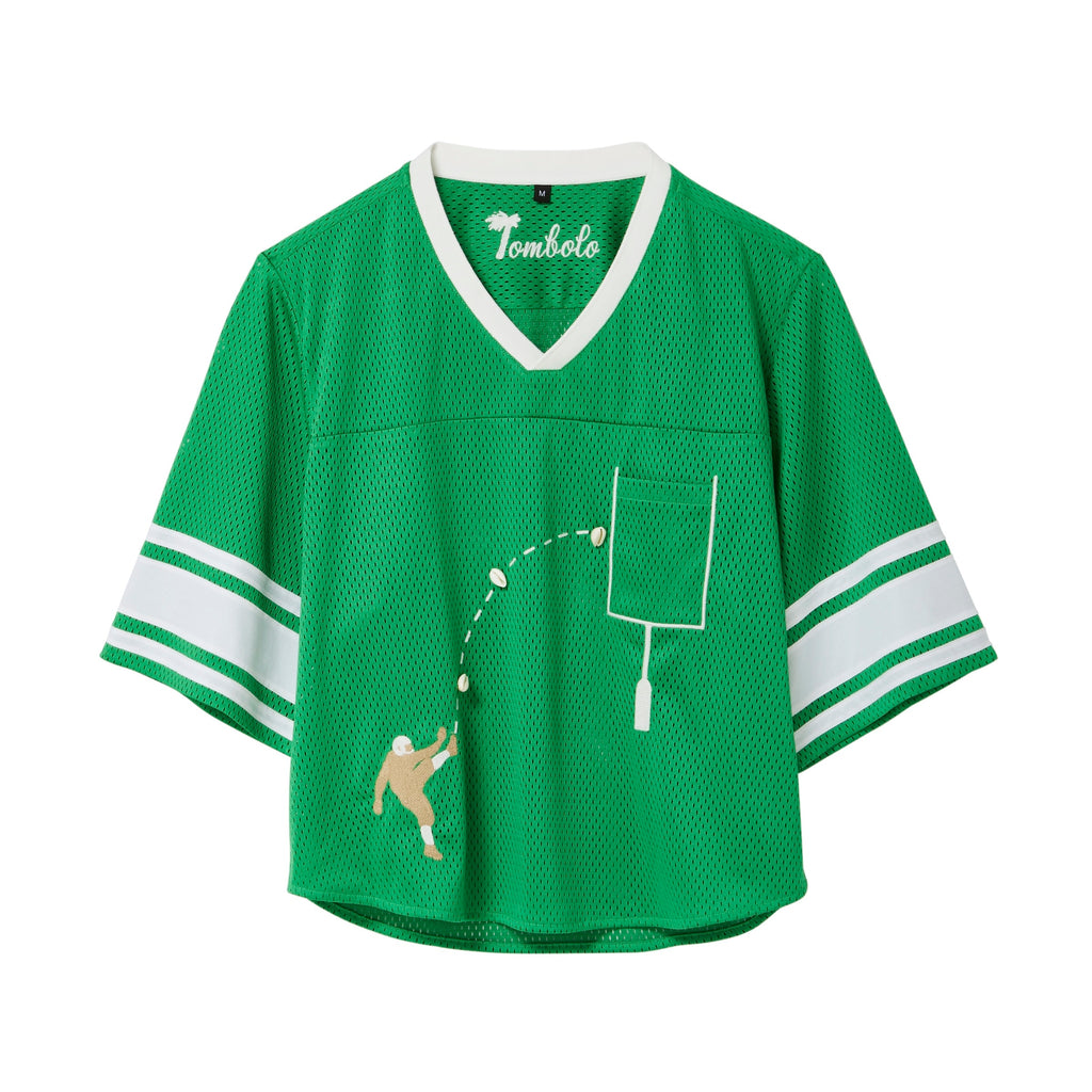 Green mesh crop-cut shirt with white stripes on the sleeves, a white V-neck, and an embroidered football design showing a player kicking a football toward a goalpost outlined around the chest pocket.