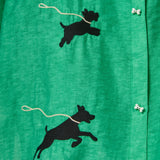 Close-up of a green cabana shirt featuring black embroidered dog silhouettes attached to white leash embroidery and dog bone–shaped buttons.