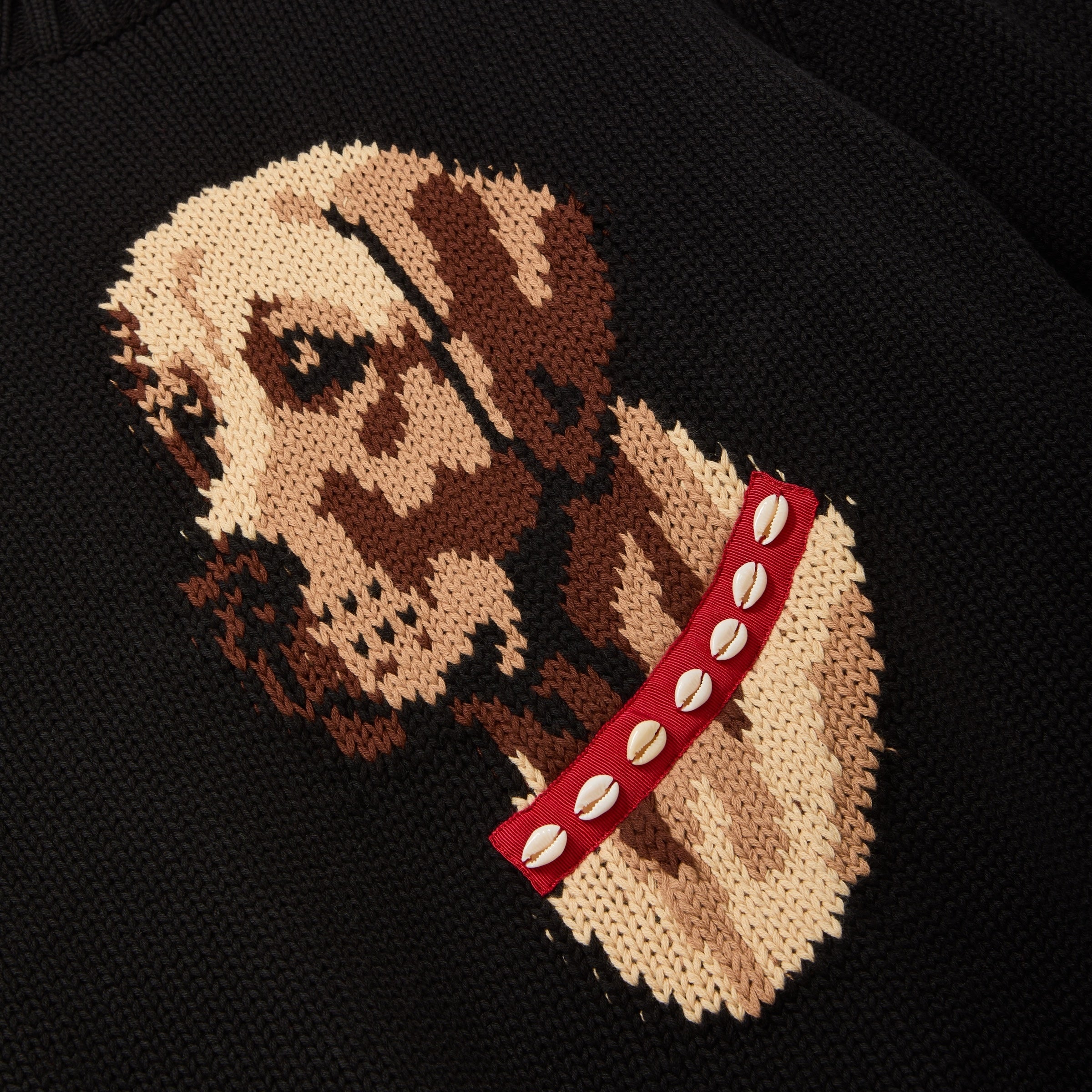 Embroidered design of a dog wearing a red collar on a black sweater.
