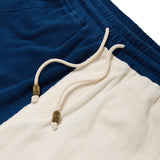 Close-up of blue and beige shorts with drawstring and brand logo.