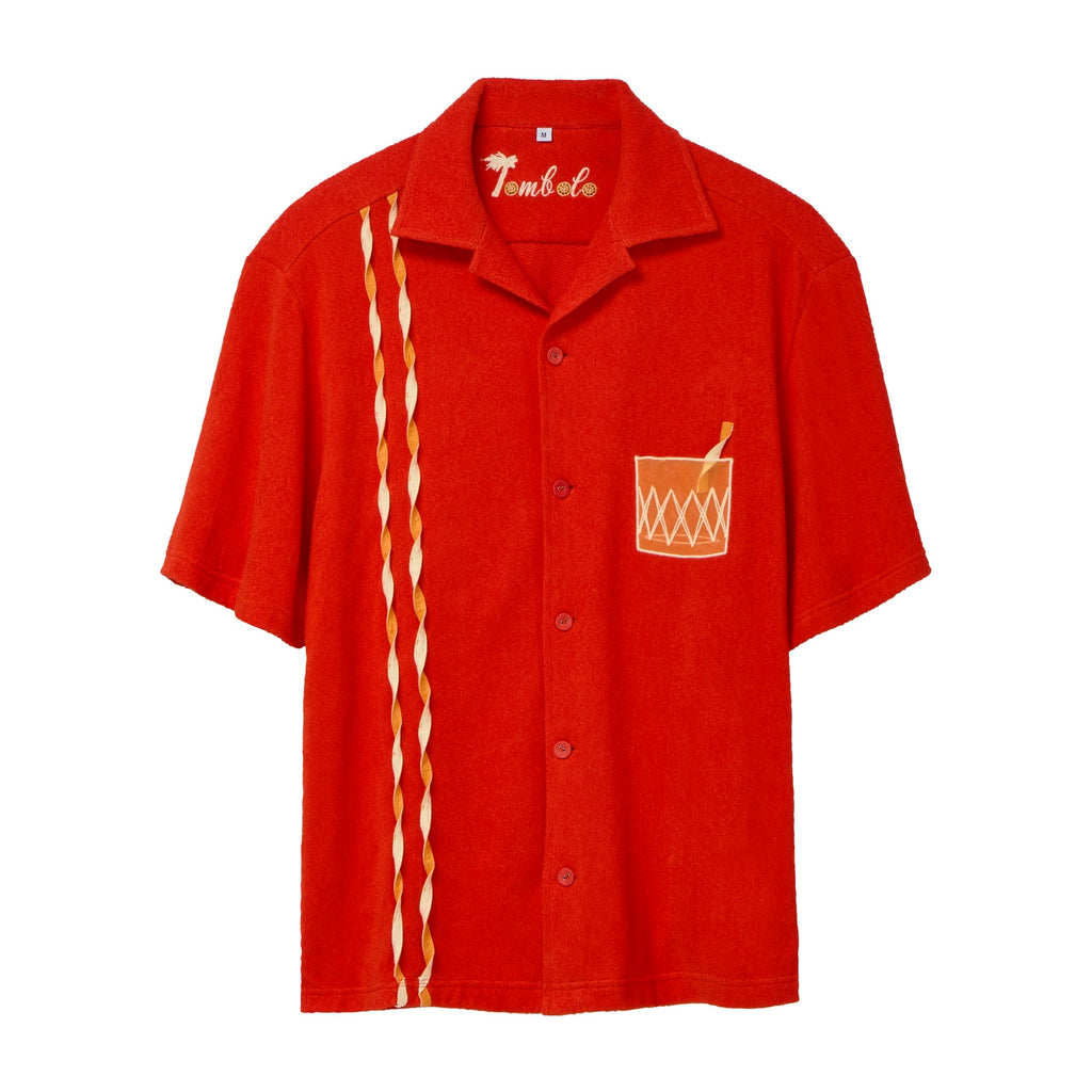 Red short-sleeve cabana shirt featuring an embroidered Negroni glass on the chest pocket and three twisted appliqué stripes running down one side. The shirt has matching red buttons and a chain-stitched “Tombolo” logo at the collar.