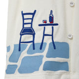 Close-up of a cream terry cabana shirt with embroidered floral vine and blue shuttered window pocket details.