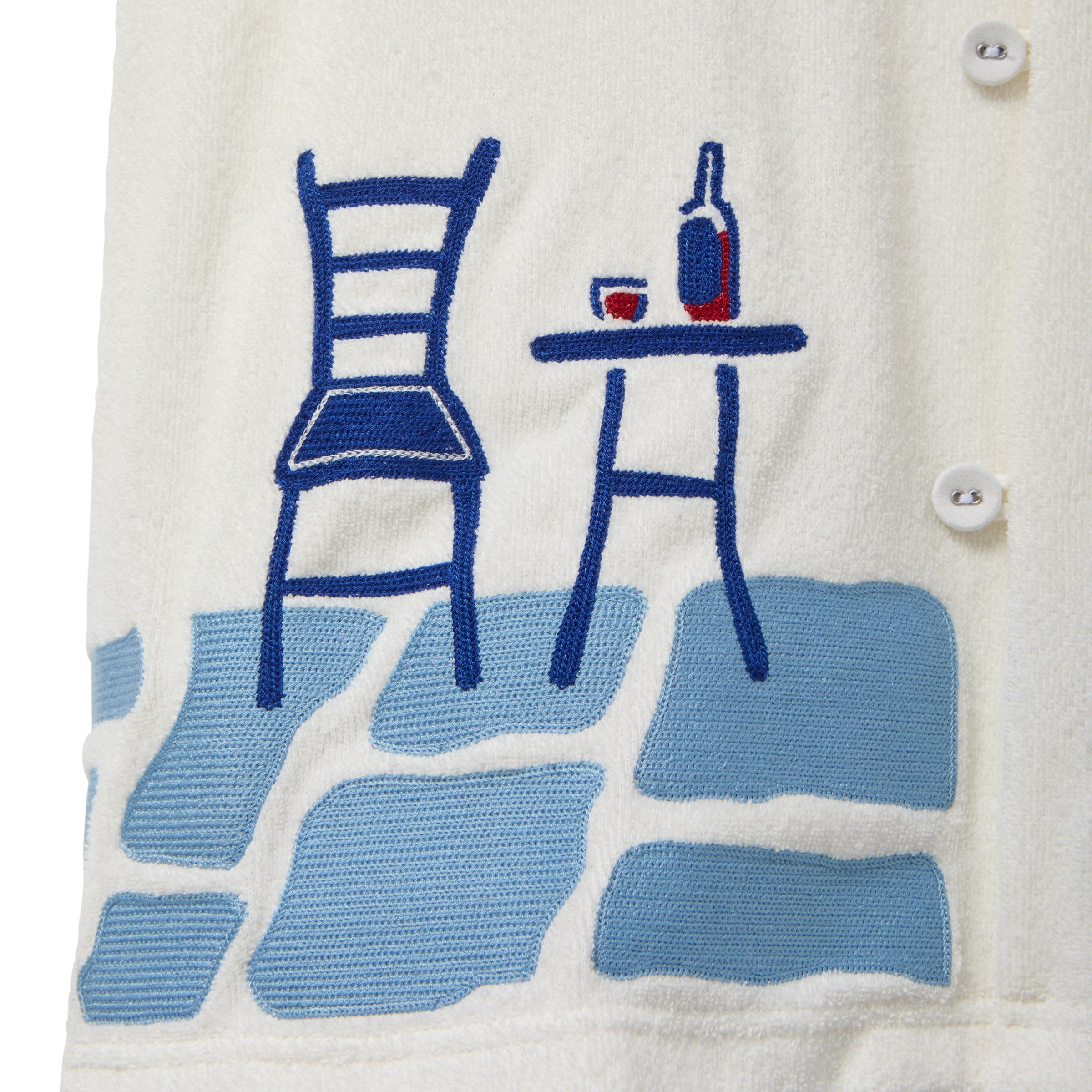 Close-up of a cream terry cabana shirt with embroidered floral vine and blue shuttered window pocket details.