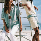 man and woman laughing and casualy leaning on lifeguard chair at the beach, wearing the terrycloth and line oyster shirts