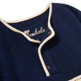Navy blue garment with white trim and 'Tombolo' branding on a white background