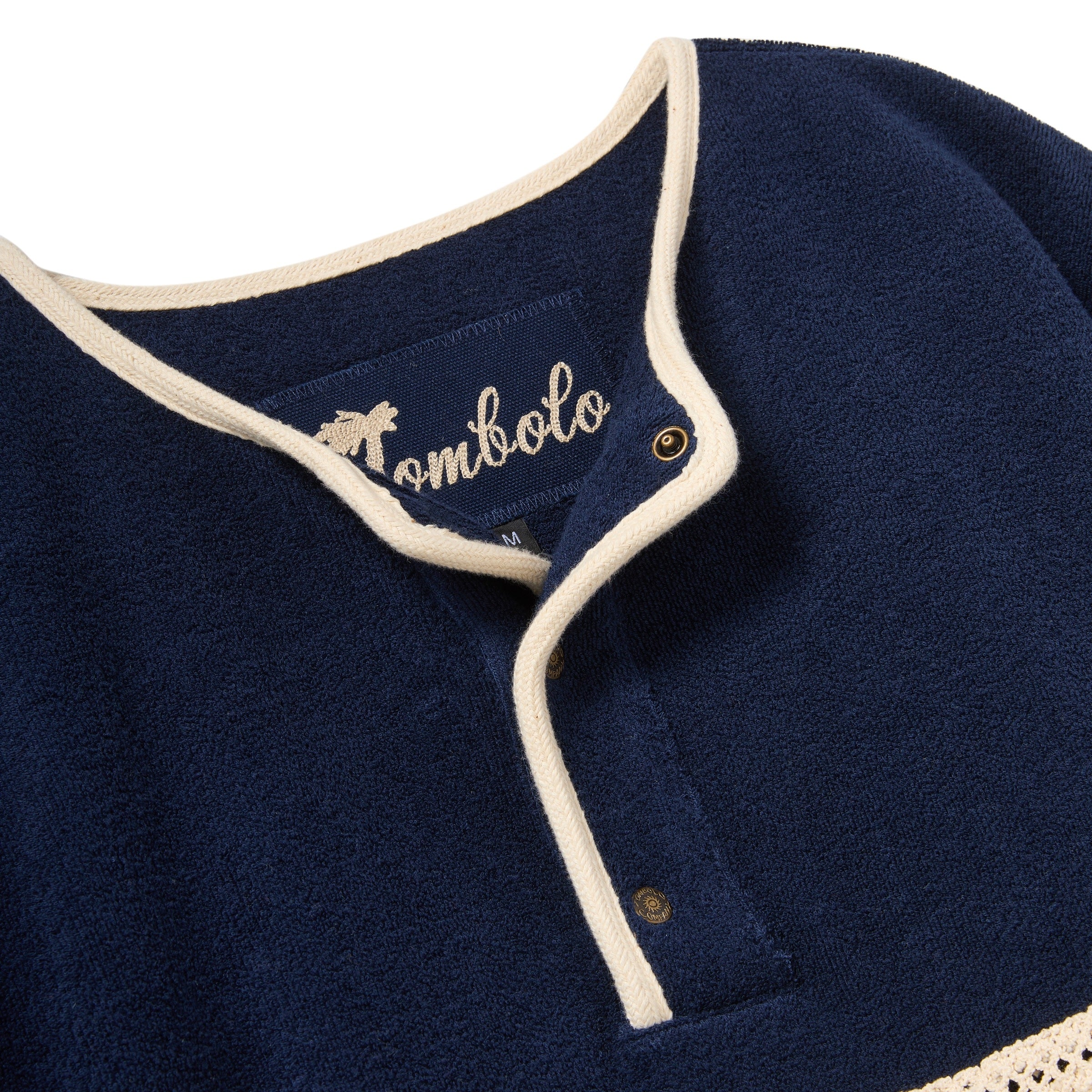 Navy blue garment with white trim and 'Tombolo' branding on a white background