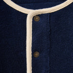 Navy blue fabric with white trim and gold buttons, featuring a brand logo.