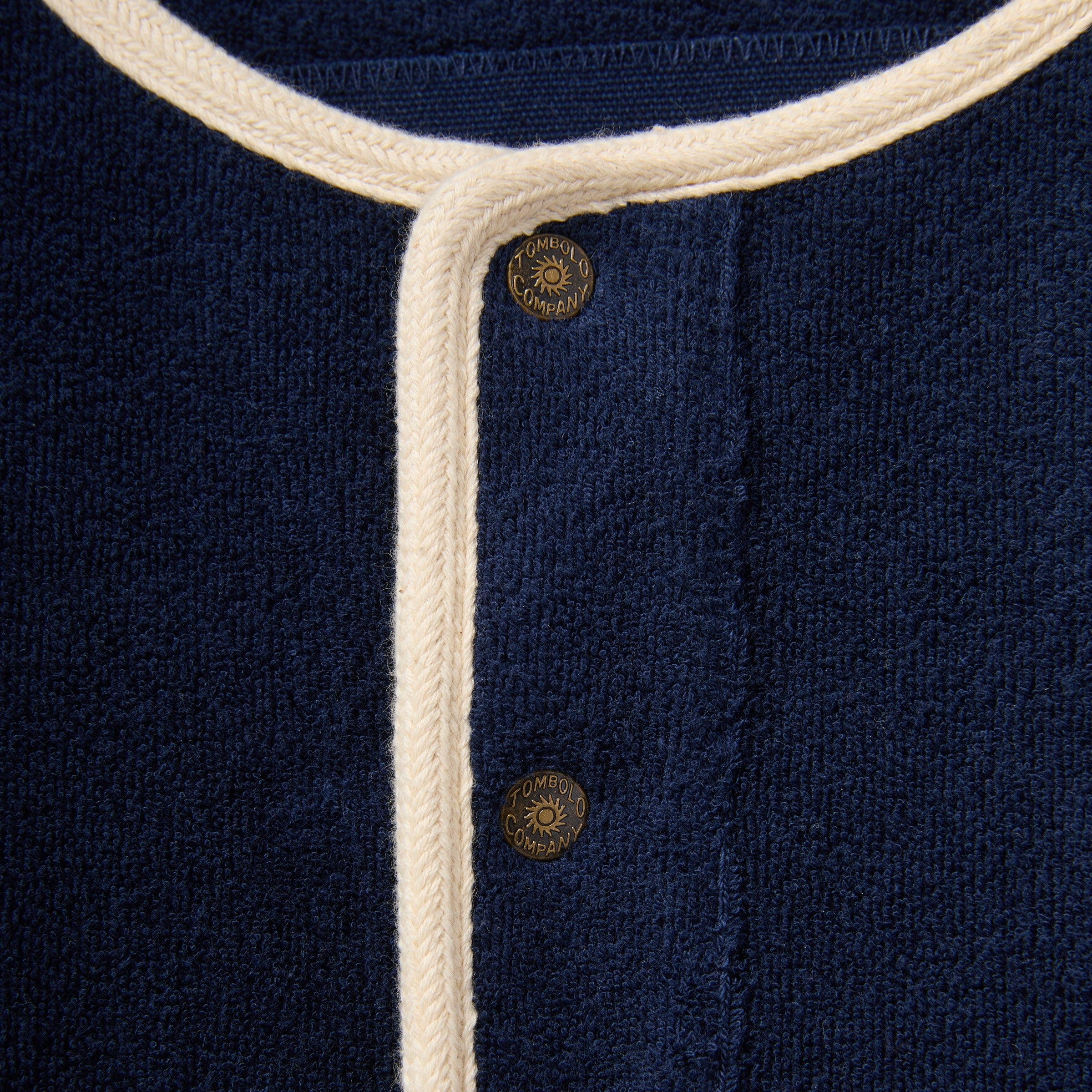 Navy blue fabric with white trim and gold buttons, featuring a brand logo.