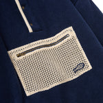 Navy blue shirt with a textured beige pocket and zipper detail