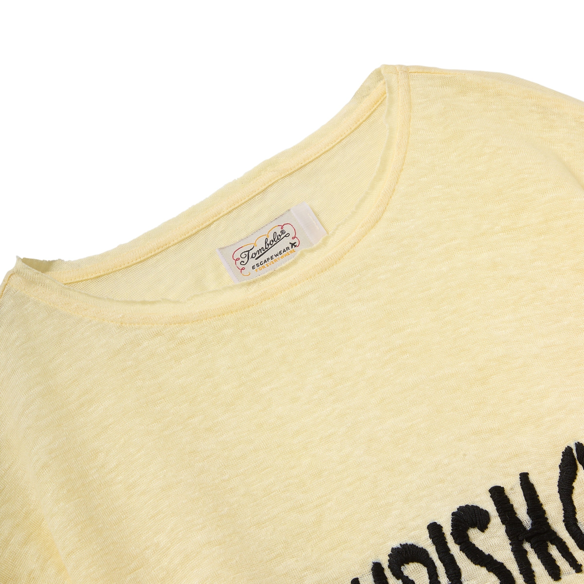 Close-up of a yellow shirt with a brand label on a white background