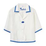 White shirt with blue trim and 'Tombolo' branding on a white background