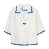 White shirt with blue trim and 'Tombolo' branding on a white background