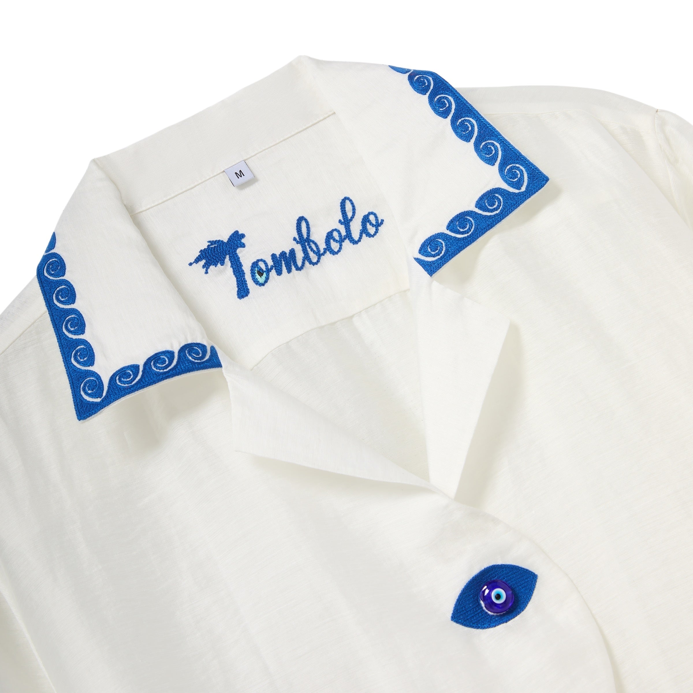 White shirt with blue embroidery and 'Tombolo' branding on a white background