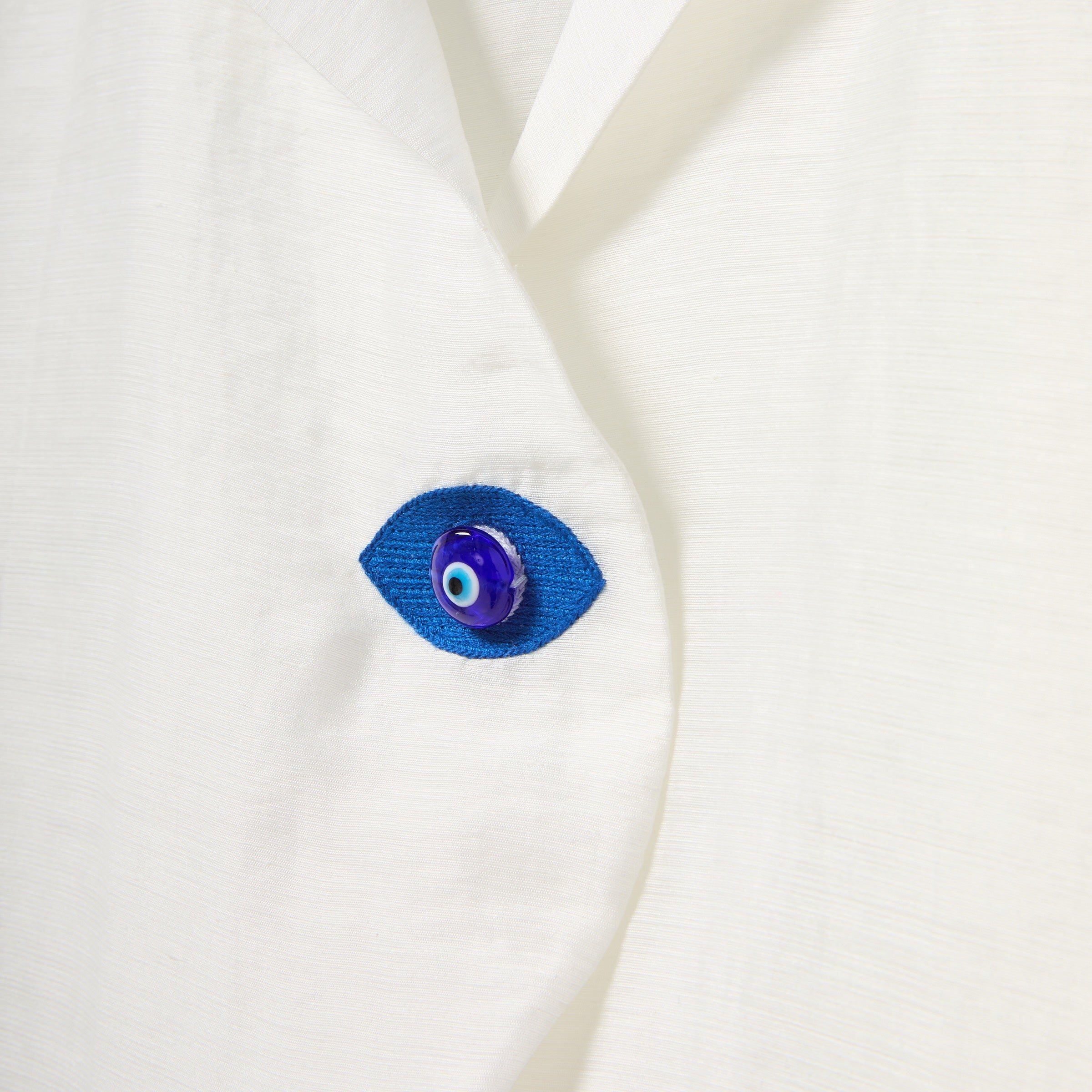 Blue eye-shaped button on a white fabric background
