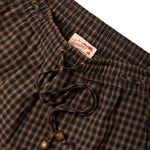 Brown and black checkered pants with a Tombolo label on a white background