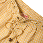 Yellow checkered shorts with a drawstring and Tombolo label on a white background
