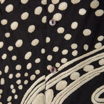 Close-up of a black fabric with beige polka dot embroidery.