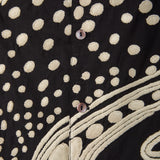 Close-up of a black fabric with beige polka dot embroidery.